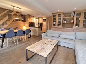 A modern interior with a dining area, sofa, and kitchen.