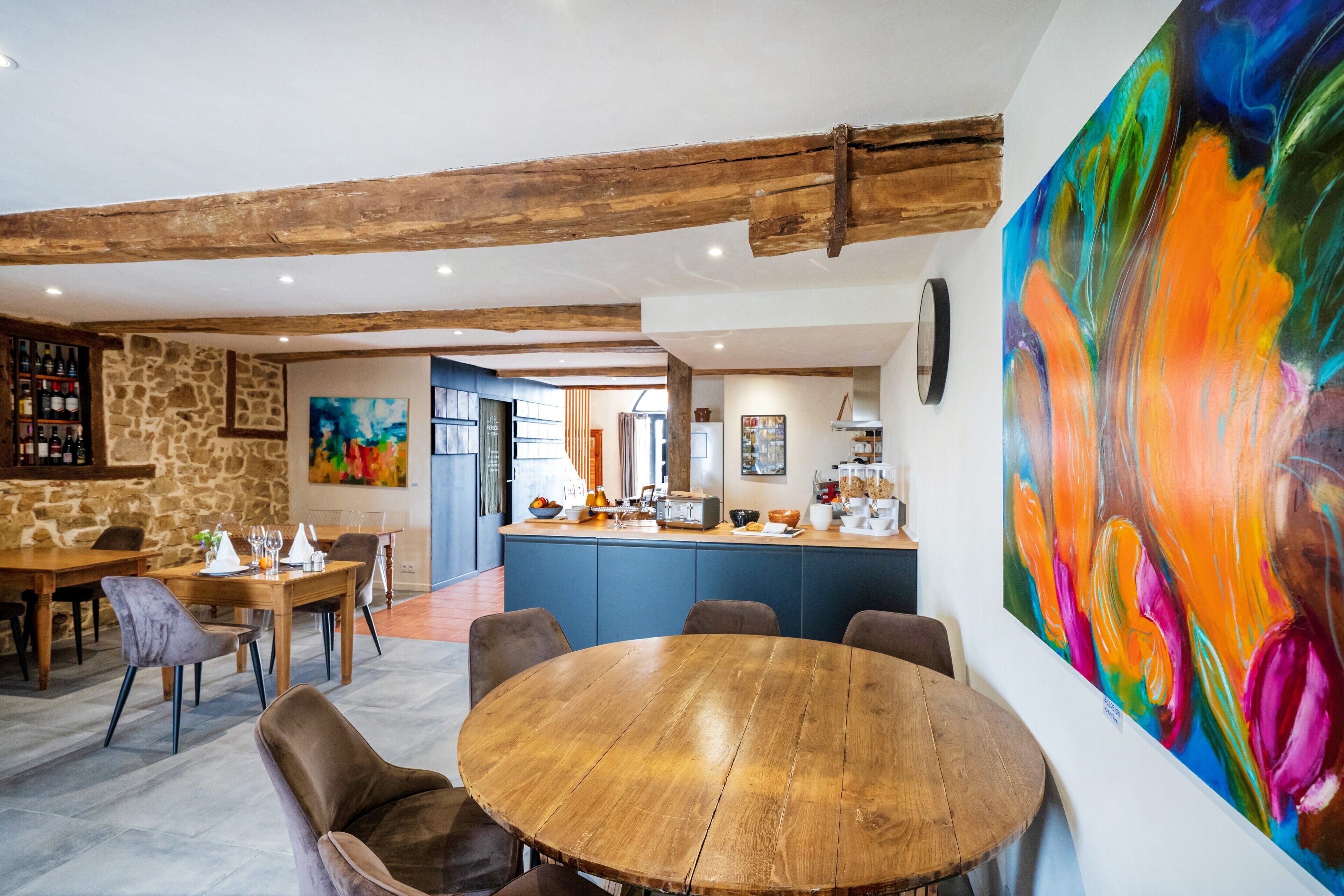 A dining area with a round wooden table, chairs, and a stone wall.
