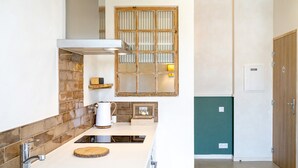 Une cuisine moderne avec un plan de travail blanc, une cuisinière encastrée et un pare-feu en bois.