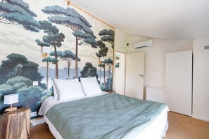 Un dormitorio con cama, mesita de noche, lámpara de pared y una puerta.