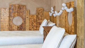 Una habitación con cama, cabecero de madera y una lámpara fijada a la pared.