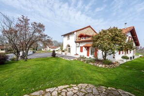 Ein zweistöckiges Haus mit Naturstein-Fassade, rotem Dach und einem gepflegten Rasen.