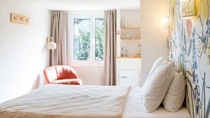 Un dormitorio con una cama, una silla, un ventanal y una pared con estante.