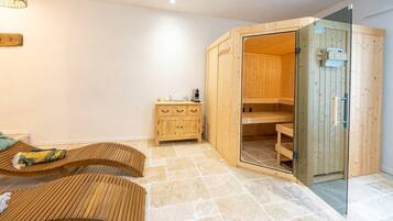 Een sauna met houten banken, een glazen deur en een klein houten kastje met een verwarming.
