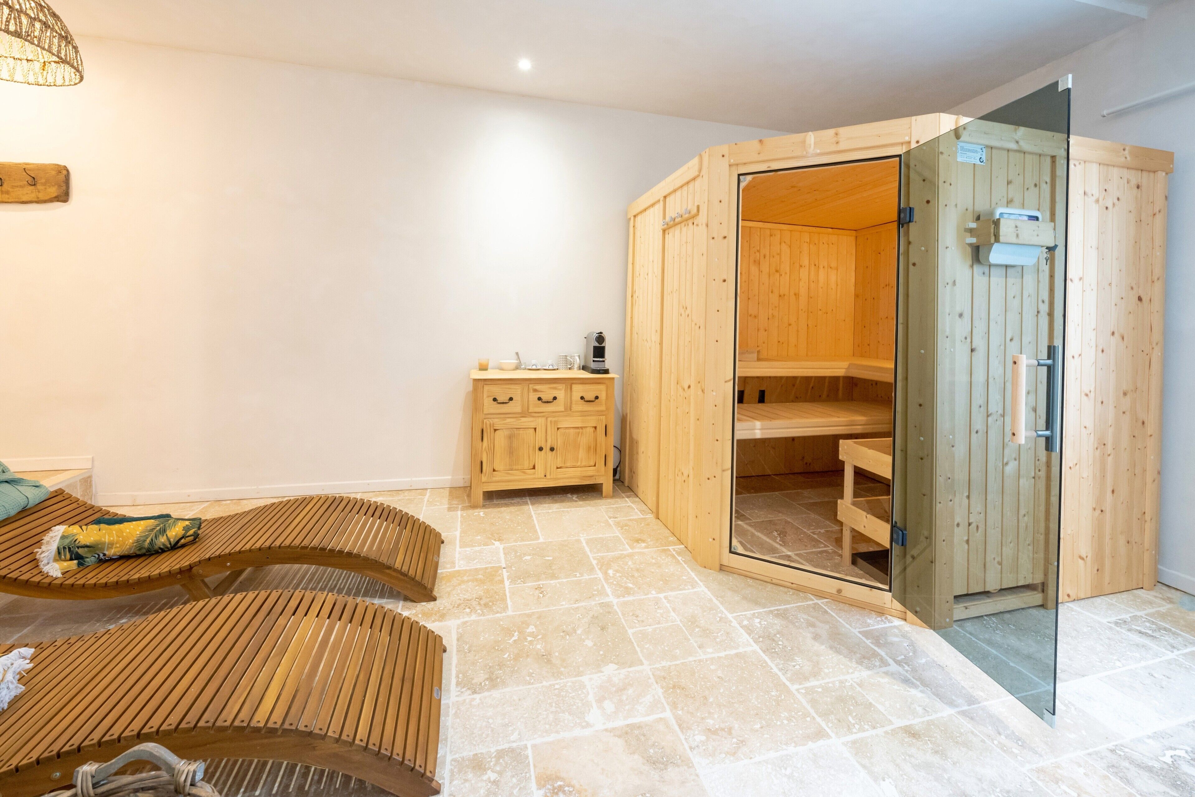 Een sauna met houten banken, een glazen deur en een klein houten kastje met een verwarming.