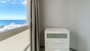 A balcony with a view of the sea and a white cabinet.