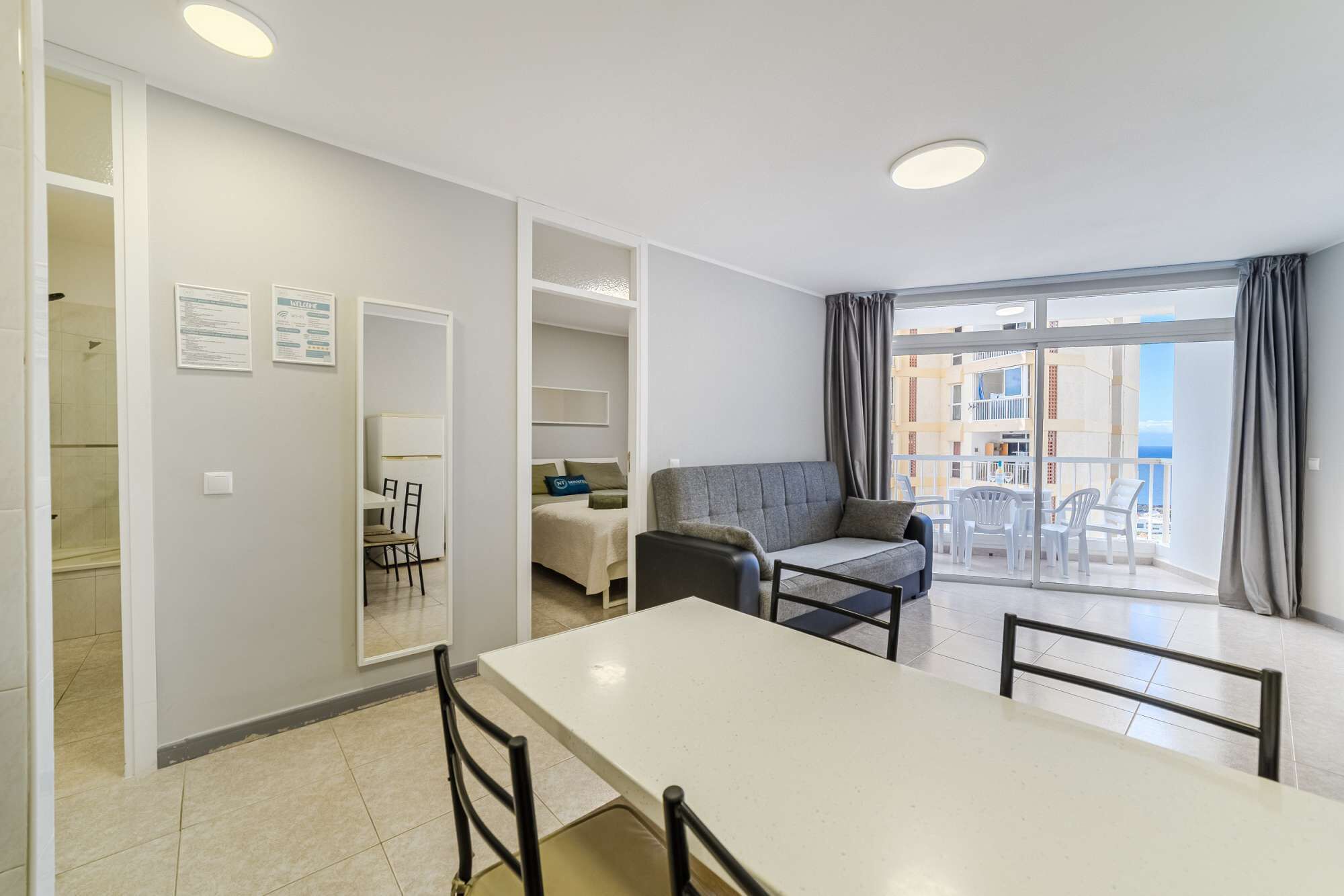 En moderne lejlighed med spiseområde, sofa og en balkon med udsigt.