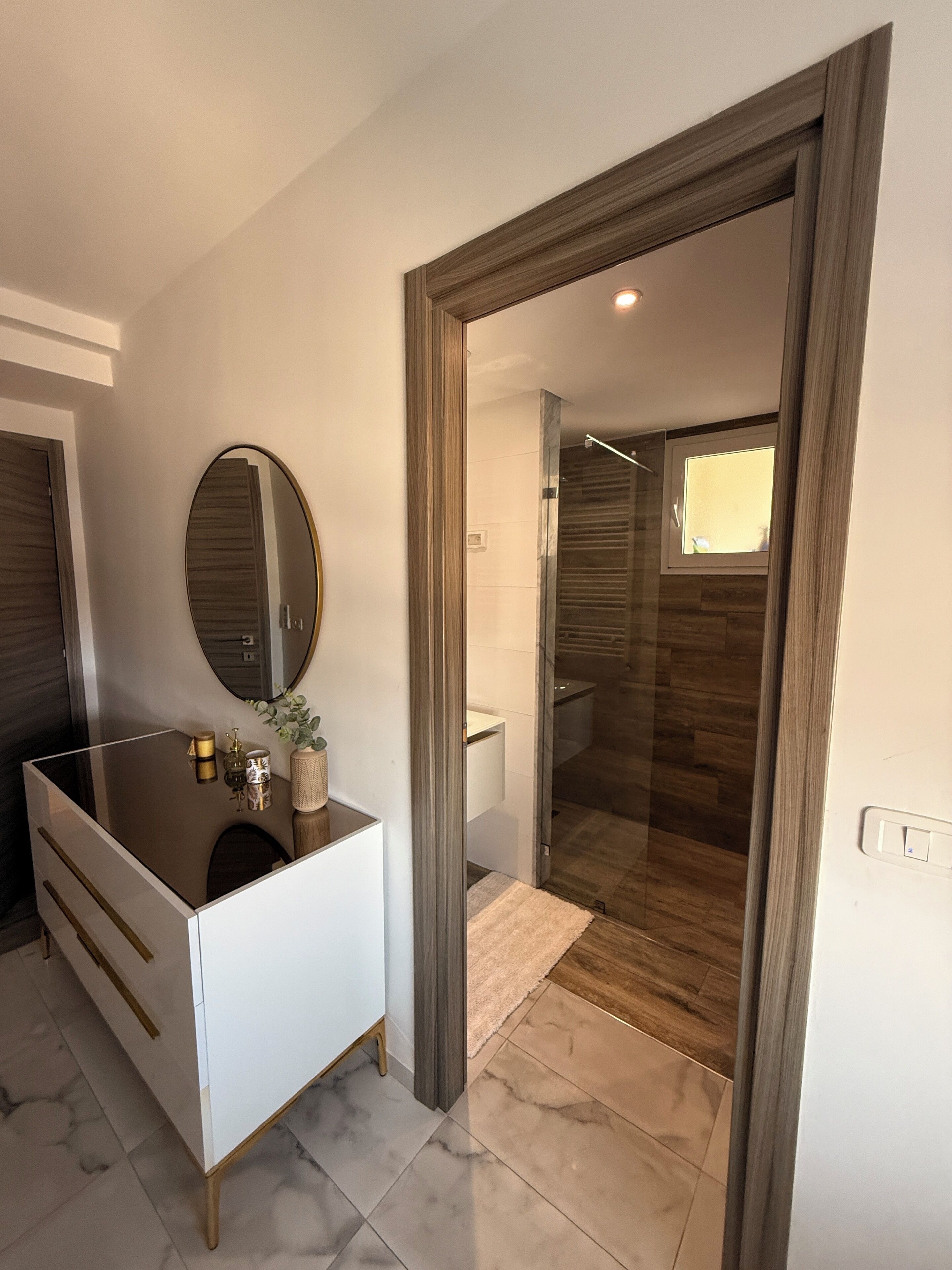 A modern bathroom with a vanity, mirror, and shower area.