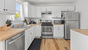 A modern kitchen with white cabinets, stainless steel appliances, and wooden countertops. - Shem Shack-Old Village, 5 mins to Beach (Mount Pleasant)