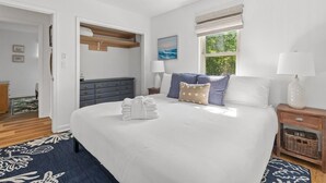 A bedroom with a large bed, a nightstand, a dresser, a window with a view, and a ceiling fan. - Shem Shack-Old Village, 5 mins to Beach (Mount Pleasant)