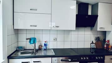 Et moderne køkken med hvide skabe, en sort bordplade, stålstål-hvidevarer og en synlig stikkontakt.