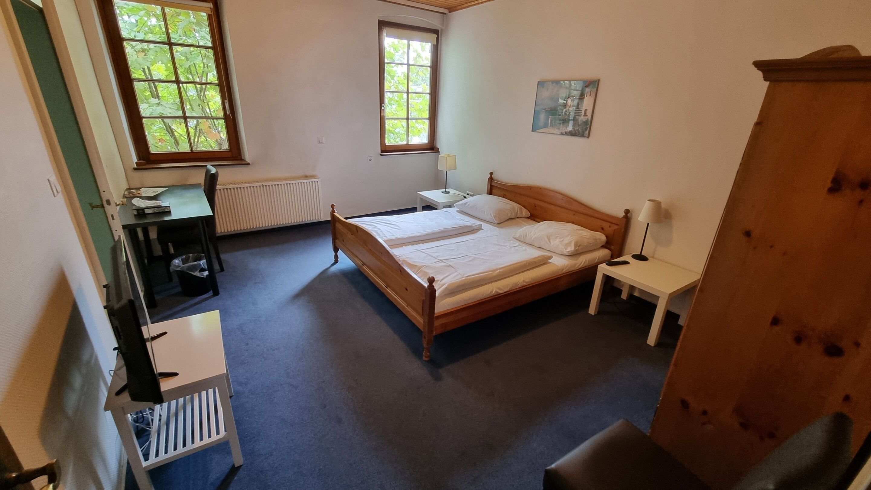 Ein Schlafzimmer mit einem Holzbett, zwei Nachttischen, einem Schreibtisch und einer Heizung.
