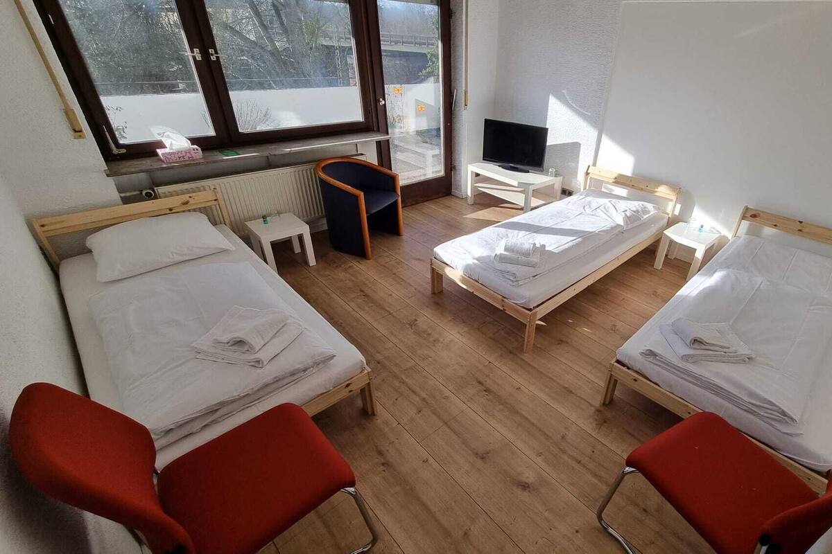 A room with two single beds, a TV, a small table, and a chair.