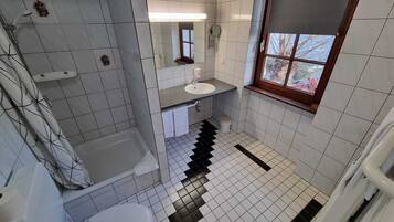 A bathroom with a bathtub, a sink, and a window.