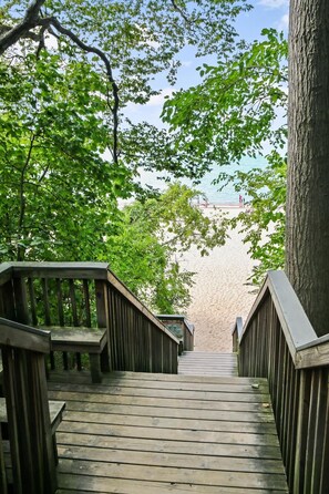 A wooden boardwalk leading to a beach with a sandy shore and a clear sky. - Luxe by the Lake | Pool Access | Near Downtown and Lake (Union Pier)