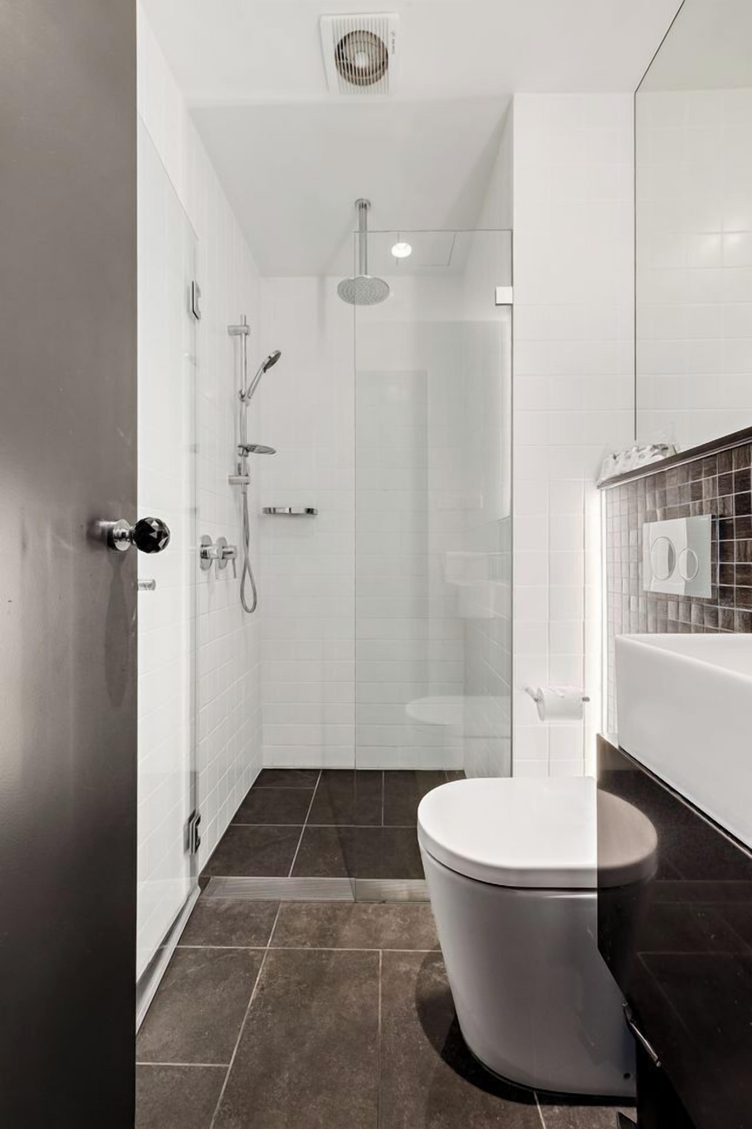 A modern bathroom with a toilet, shower, and glass-enclosed shower area.