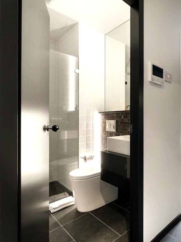 Ein modernes Badezimmer mit Toilette, Duschkabine aus Glas und Waschbecken.