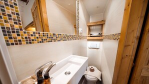 Une petite salle de bain avec un lavabo blanc, des toilettes et une petite étagère au-dessus des toilettes.
