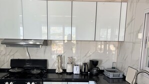 A modern kitchen with white cabinets, a black stove, and stainless steel appliances. - Beach Front 2 Bed Condon C1.1 with Sea View and Private Pool !! (Simpson Bay)
