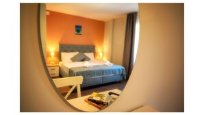 Une chambre d’hôtel avec un lit, des tables de chevet et une petite table avec des livres.