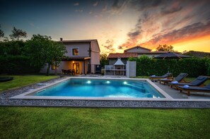 Ein Schwimmbad mit Liegestühlen, einer Grillmöglichkeit und einem Haus mit Terrasse.