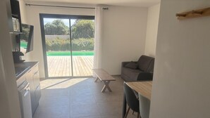 Eine moderne Küche mit Essbereich, einer Couch und einer Holzdiele mit Blick auf eine grüne Landschaft.