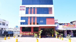 A hotel named SY21 with a modern facade, large windows, and a red brick section. - HOTEL SY21 (Dhar)