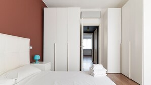 Une chambre à coucher avec un lit, une armoire blanche et une table de chevet avec une lampe.