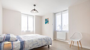 A bedroom with a bed, a chair, a lamp, and a window.