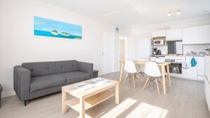 A modern living room with a grey sofa, a wooden coffee table, and a painting of a beach scene.
