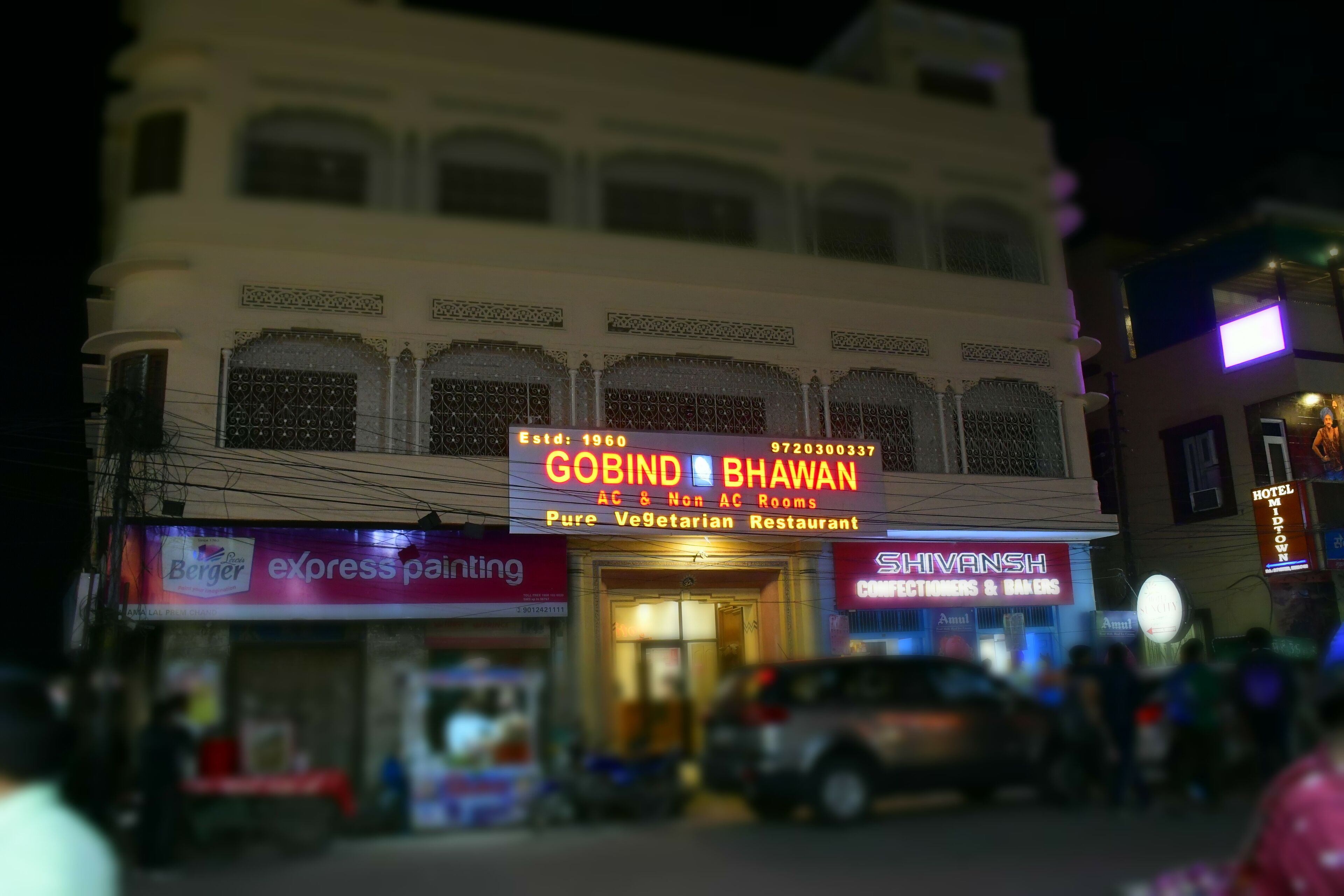 A building with a sign for 'GOBIND BHAVAN' offering AC & Non-AC rooms and a vegetarian restaurant.