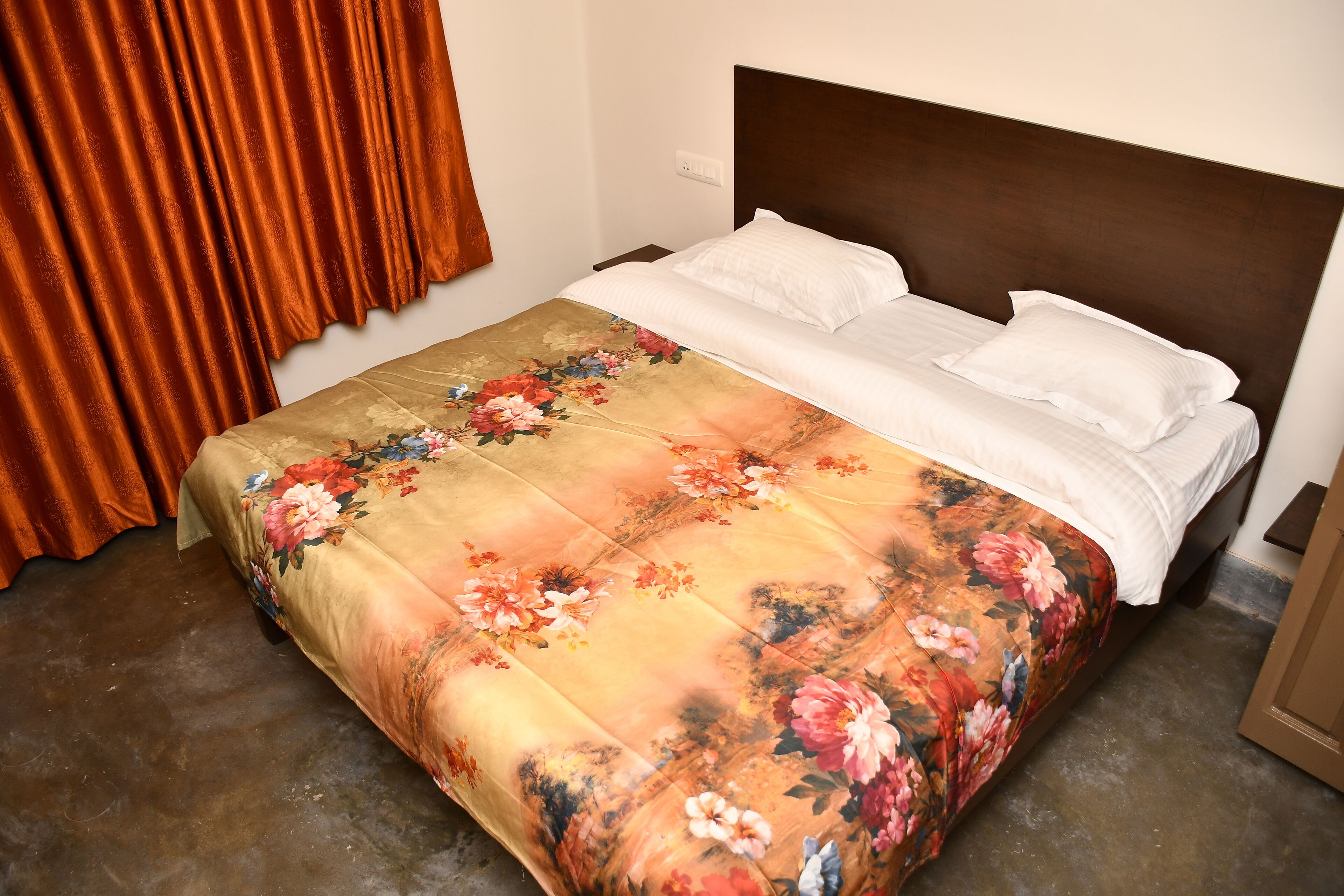 A bed with a floral bedspread, a wooden headboard, and a nightstand with a lamp.