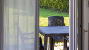 An open door leading to a patio area with a table and chairs. - Apartment 'Penfret' with Private Terrace, Shared Garden and Wi-Fi (Fouesnant)