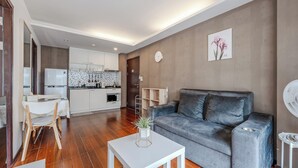 Una sala moderna con un sofá gris, una mesa de centro blanca y una zona de comedor con una mesa y sillas blancas.