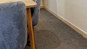 A room with a wooden table, a grey chair, a round mirror on a wooden shelf, and a carpeted floor. - VESTA - New Cairo Residennce (New Cairo)
