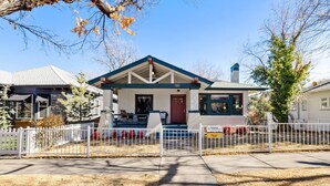 A single-story house with a front porch, a chimney, and a fenced yard.