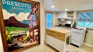 A modern kitchen with a white stove, microwave, and cabinets. There is a framed picture of Prescott, Arizona on the wall.