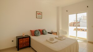 A bedroom with a bed, nightstands, a chair, a window, and a balcony view.