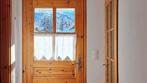 A wooden door with a window, a doormat, and a wall-mounted hook. - Chalet with panoramic view · Modern comfort · Quick access to 3 Vallées (Les Belleville)