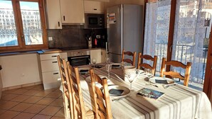 A kitchen with a dining area, including wooden chairs, a table set for a meal, and a refrigerator. - Chalet with panoramic view · Modern comfort · Quick access to 3 Vallées (Les Belleville)