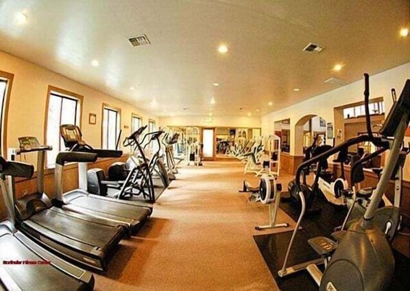 Un gimnasio con cintas de correr, elípticas y bicicletas estáticas.