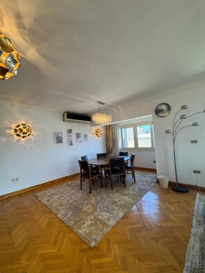 Un coin repas avec une table et des chaises en bois, un tapis Ă motifs et un lustre moderne.