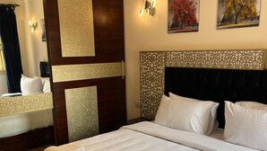 A hotel room with a large bed, a wooden headboard, a mirror, and two paintings on the wall. - VESTA - Mohandessin (Giza)