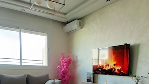 Een moderne woonkamer met een bank, salontafel en een aan de muur bevestigde televisie.