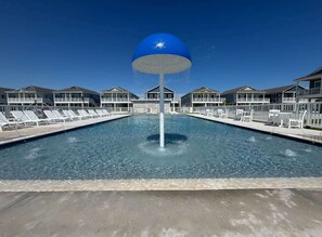 A swimming pool with lounge chairs and a large blue water feature in the center.