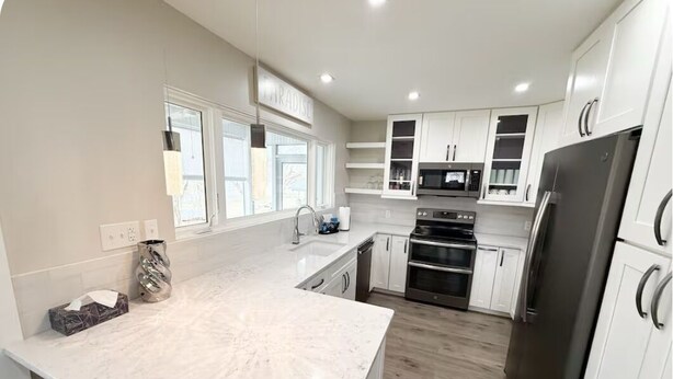 A modern kitchen with white cabinets, a stainless steel refrigerator, and a built-in oven. - 2 Bedroom Riverfront House on the New River Trail (Allisonia)
