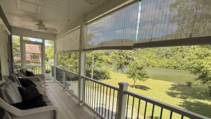 A covered porch with wicker furniture and a view of a lake. - 2 Bedroom Riverfront House on the New River Trail (Allisonia)