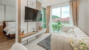 Een moderne hotelkamer met een groot bed, een aan de muur bevestigde televisie, een bank en uitzicht op de stad.