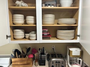 A kitchen with white cabinets, a wooden spice rack, a toaster, and a coffee maker. - Walk to Downtown CDA | Sleeps 8 | Arcade + Pets (Coeur d'Alene)