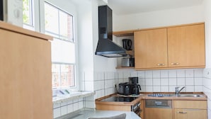 Een functionele keuken met een fornuis, koffiezetapparaat en vaatwasser.